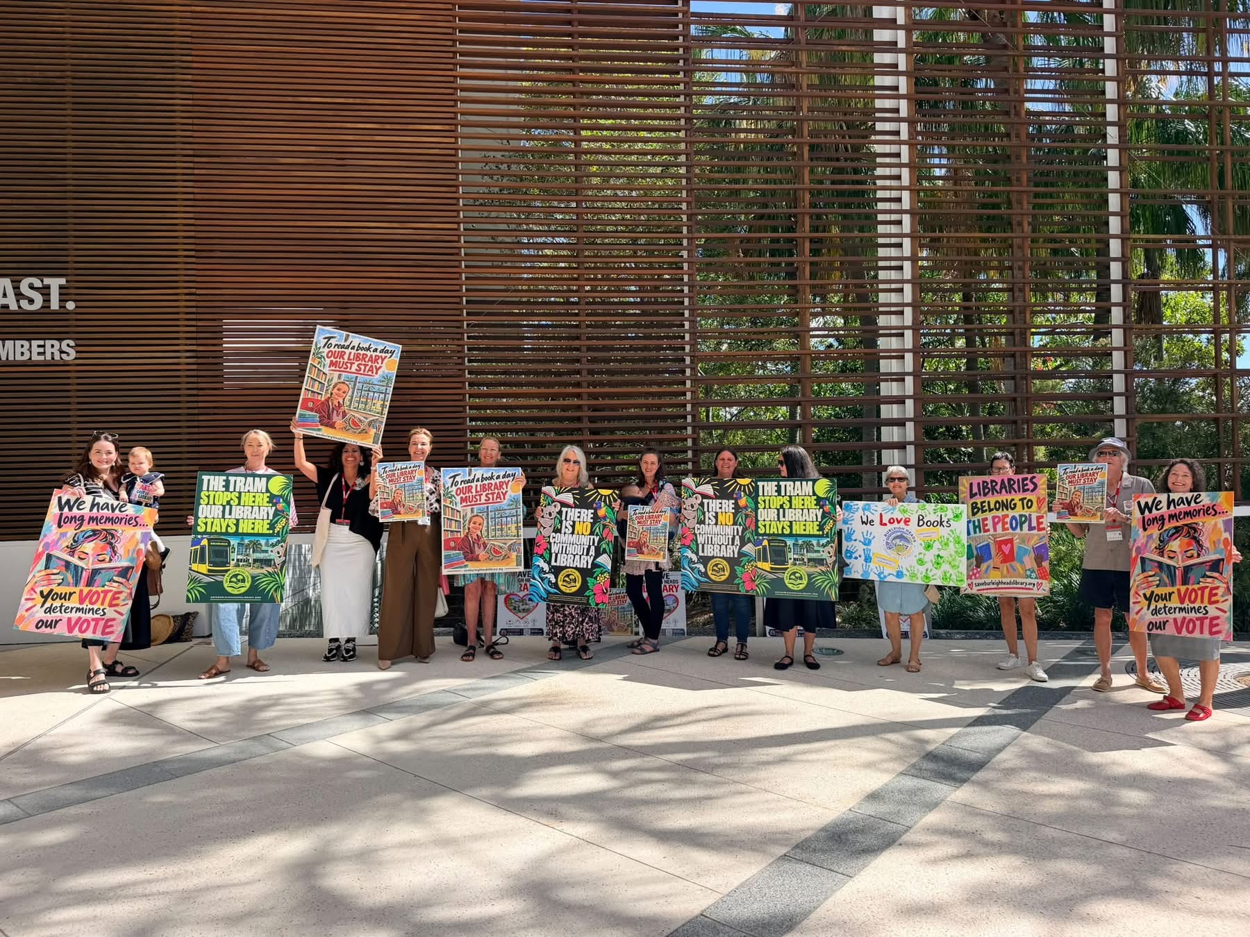 A line of campaigners holding colourful campaign posters outside council chambers
