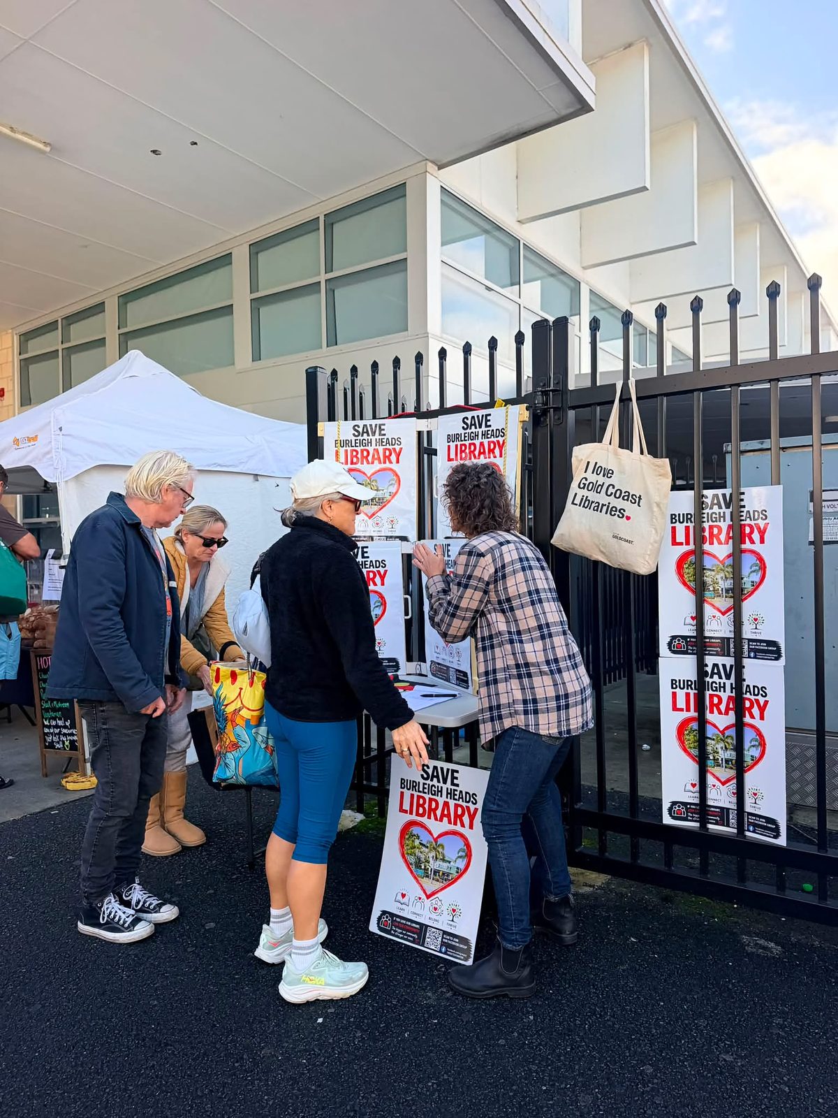 Campaign volunteers with Save Burleigh Heads Library signs at a local market stall