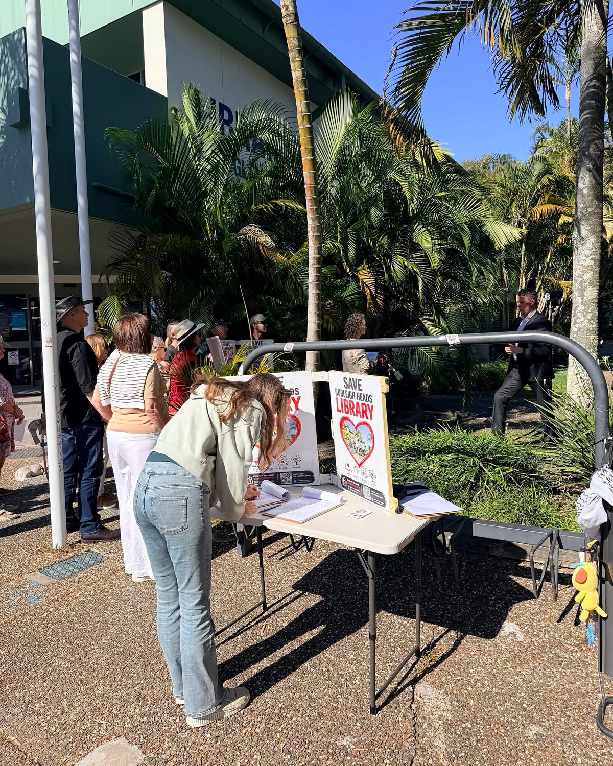 Residents signing the petition at a table outside the library